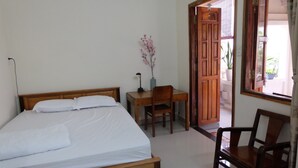 A bedroom with a wooden bed, a desk, and a chair. There is a vase with flowers on the desk. - Moon House Nha Trang (Nha Trang)