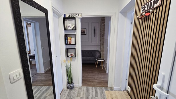 A hallway with a wooden bench, a mirror, and a sign indicating an exit. - Apartmani M&L (Medulin)
