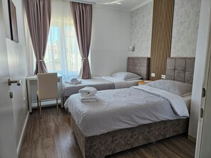 Ett hotellrum med två sängar, ett skrivbord och en stol.