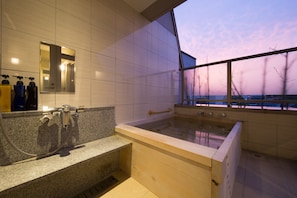 A modern bathroom with a granite countertop, a large bathtub, and a window with a view of the sky. - Bansyoukaku Shikishima (Ureshino)