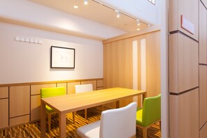 A modern meeting room with a wooden table, white and green chairs, a framed picture on the wall, and a light-colored floor. - Bansyoukaku Shikishima (Ureshino)
