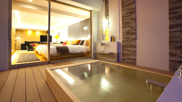 A modern bedroom with a glass door leading to a bathroom, a wooden deck, and a spa area. - Bansyoukaku Shikishima (Ureshino)