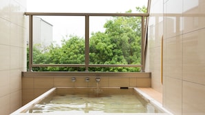 A modern bathroom with a large bathtub, a window with a view of greenery, and tiled walls. - Bansyoukaku Shikishima (Ureshino)