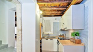 Uma cozinha compacta com armários brancos, bancada de madeira e painel de azulejos.