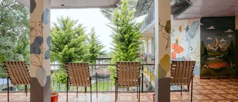 Un espacio de estar techado al aire libre con sillas y vistas a un jardín y árboles.