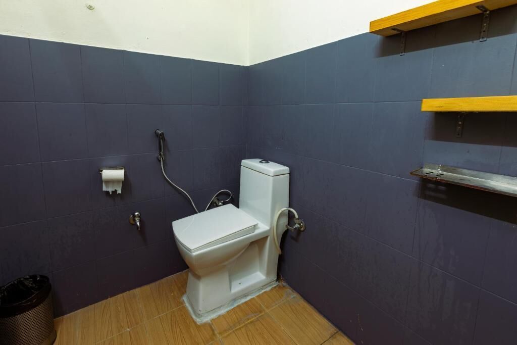 A small bathroom with a white toilet, a shower, and a wooden floor.