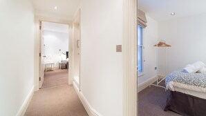 A hotel room with a bed, a desk, and a chair. There is a window with a view of the outside. - PML Apartments Park Road (London)