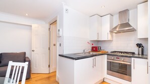 A compact kitchen with white cabinets, a stainless steel stove, and a built-in oven. - PML Apartments Park Road (London)