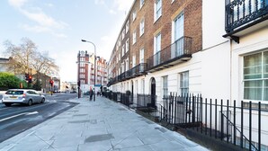 A street with a sidewalk, a car, and buildings with balconies. - PML Apartments Park Road (London)