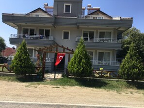 Un immeuble à plusieurs étages doté de balcons, d’un drapeau et d’une pergola.