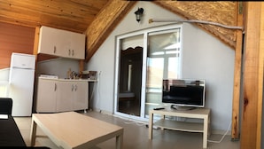 Cocina compacta con refrigerador, armarios y comedor con mesa.