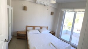 Un dormitorio con cama, mesita de noche, ventana con vistas y equipo de aire acondicionado.