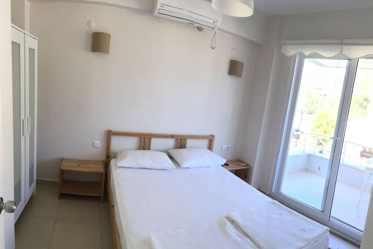 Una camera da letto con un letto, un comodino, una finestra vista e un condizionatore.