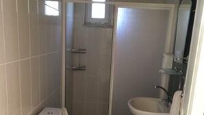 Un baño con inodoro, cabina de ducha y lavabo.