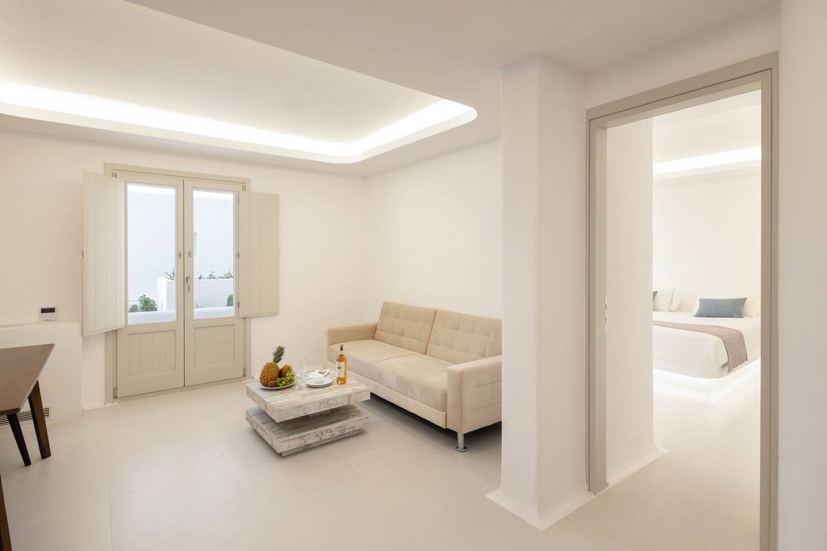 Een moderne, minimalistische woonkamer met een bank, salontafel en een eethoek.