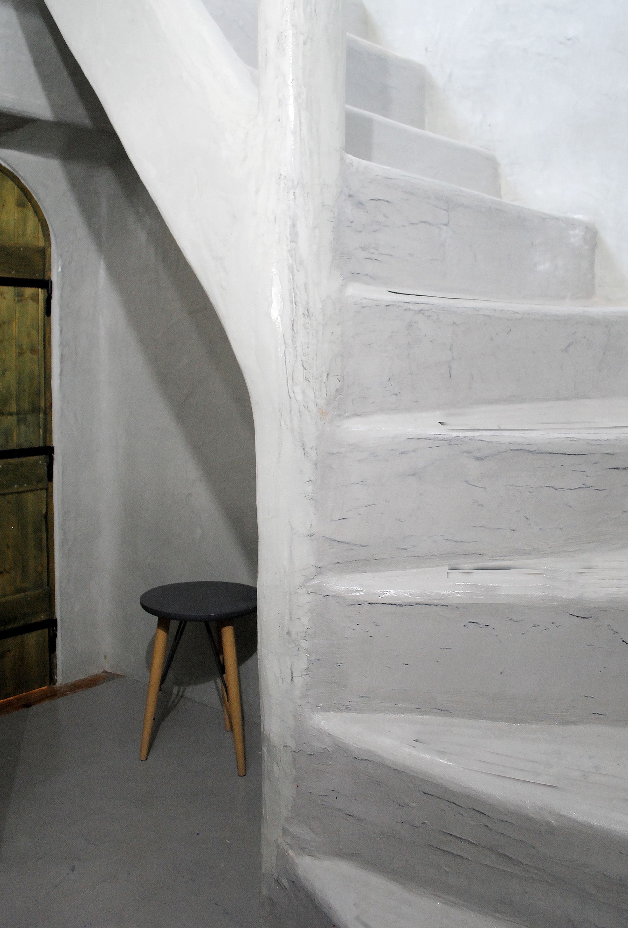 Una escalera blanca con peldaños de madera y una pequeña mesa redonda con patas de madera.