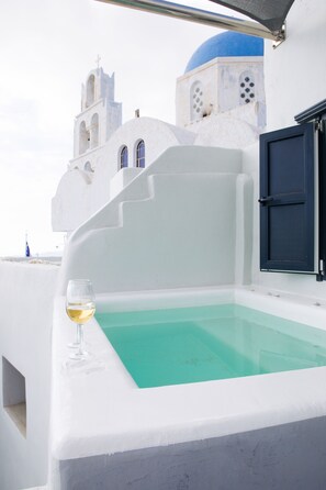 Un bâtiment blanc surmonté d’un dôme bleu et une piscine blanche dont le bord est en verre.