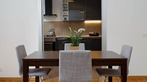 Een eethoek met een houten tafel en twee grijze gestoffeerde stoelen. Op de tafel staat een potplant.