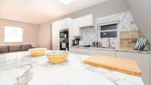 A modern kitchen with marble countertops, a skylight, and a built-in oven.