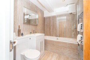 A modern bathroom with a marble vanity, a toilet, a bathtub, and a glass shower enclosure.
