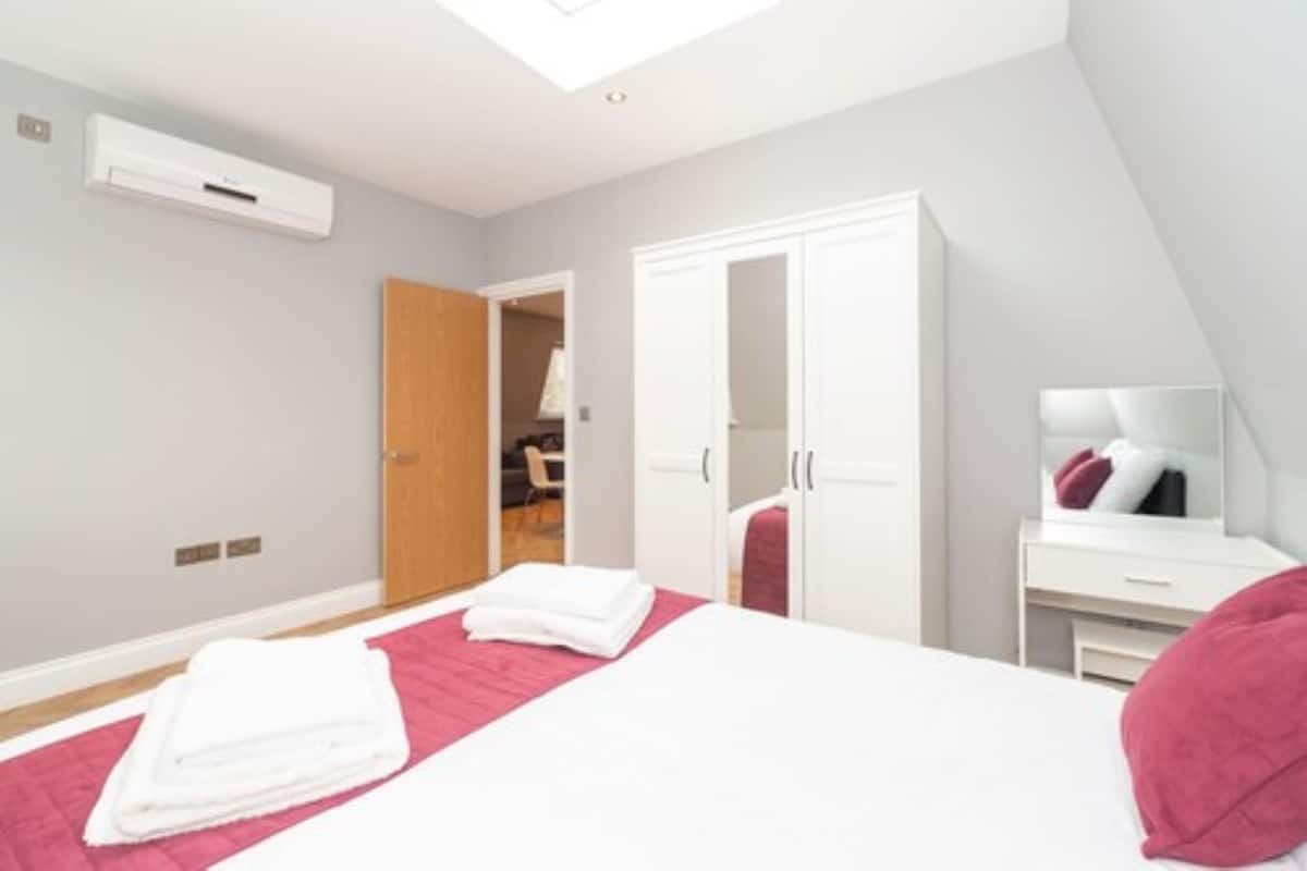 A modern hotel room with a bed, a wardrobe, a desk, and a skylight.