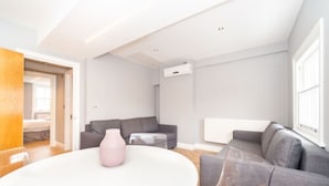A modern living room with a grey sofa, a white coffee table, and a pink vase.