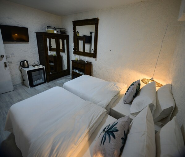 Une chambre avec deux lits, une commode, un miroir et un téléviseur fixé au mur.