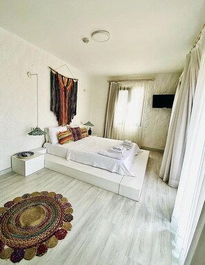Une chambre à coucher moderne avec un grand lit, une table de chevet, une lampe, un téléviseur et un tapis décoratif.