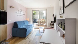 Un soggiorno moderno con un divano blu, un tavolo bianco e una porta in vetro che dà su uno spazio all'aperto.