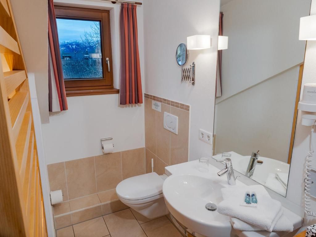 Een badkamer met toilet, wastafel en spiegel.