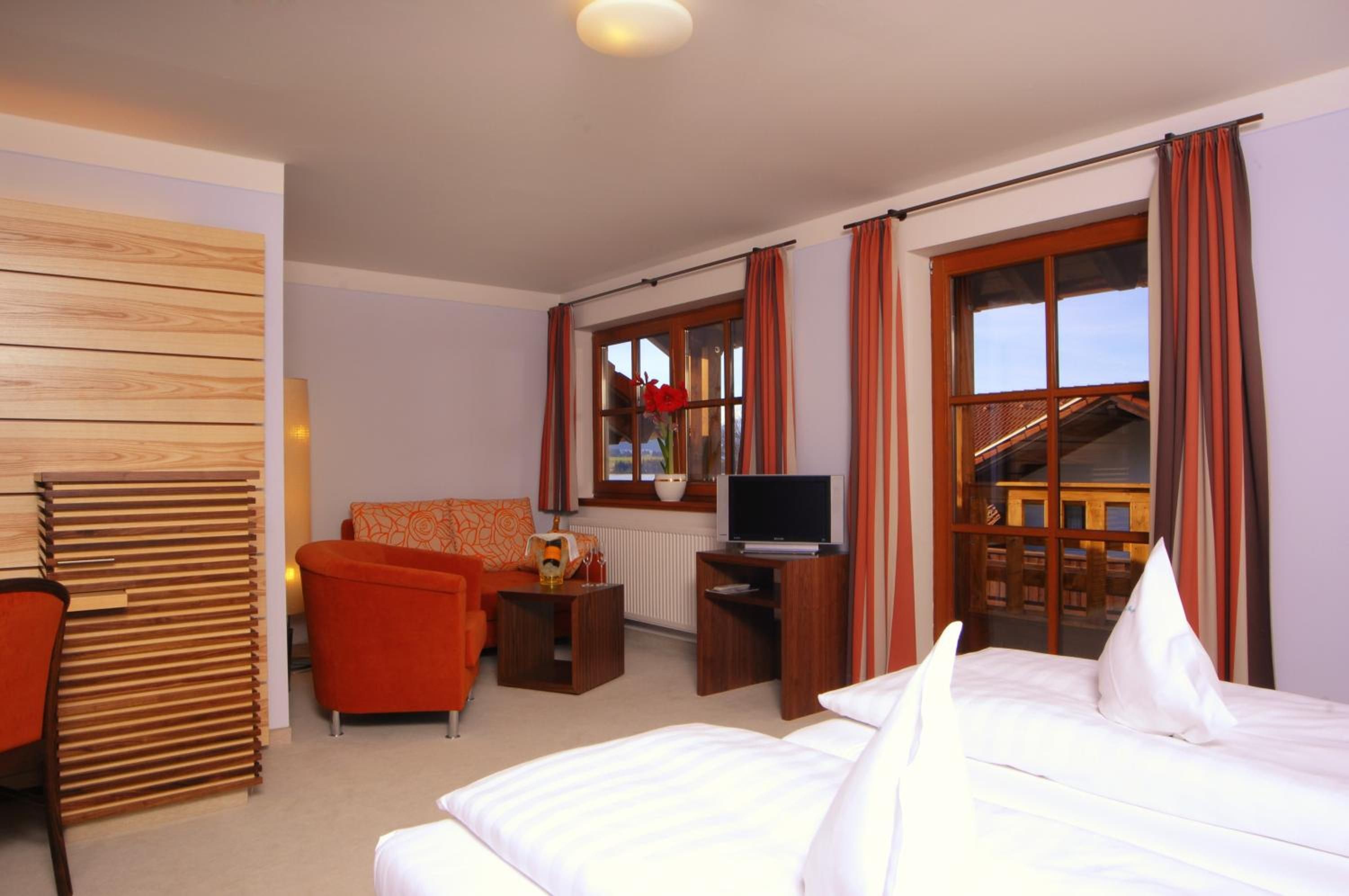 Ein Hotelzimmer mit Bett, einer Couch, einem Fernseher und einem fenster mit Vorhängen.