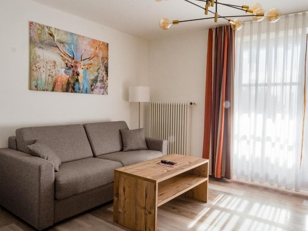 A modern living room with a sofa, a coffee table, a painting, a lamp, and curtains.