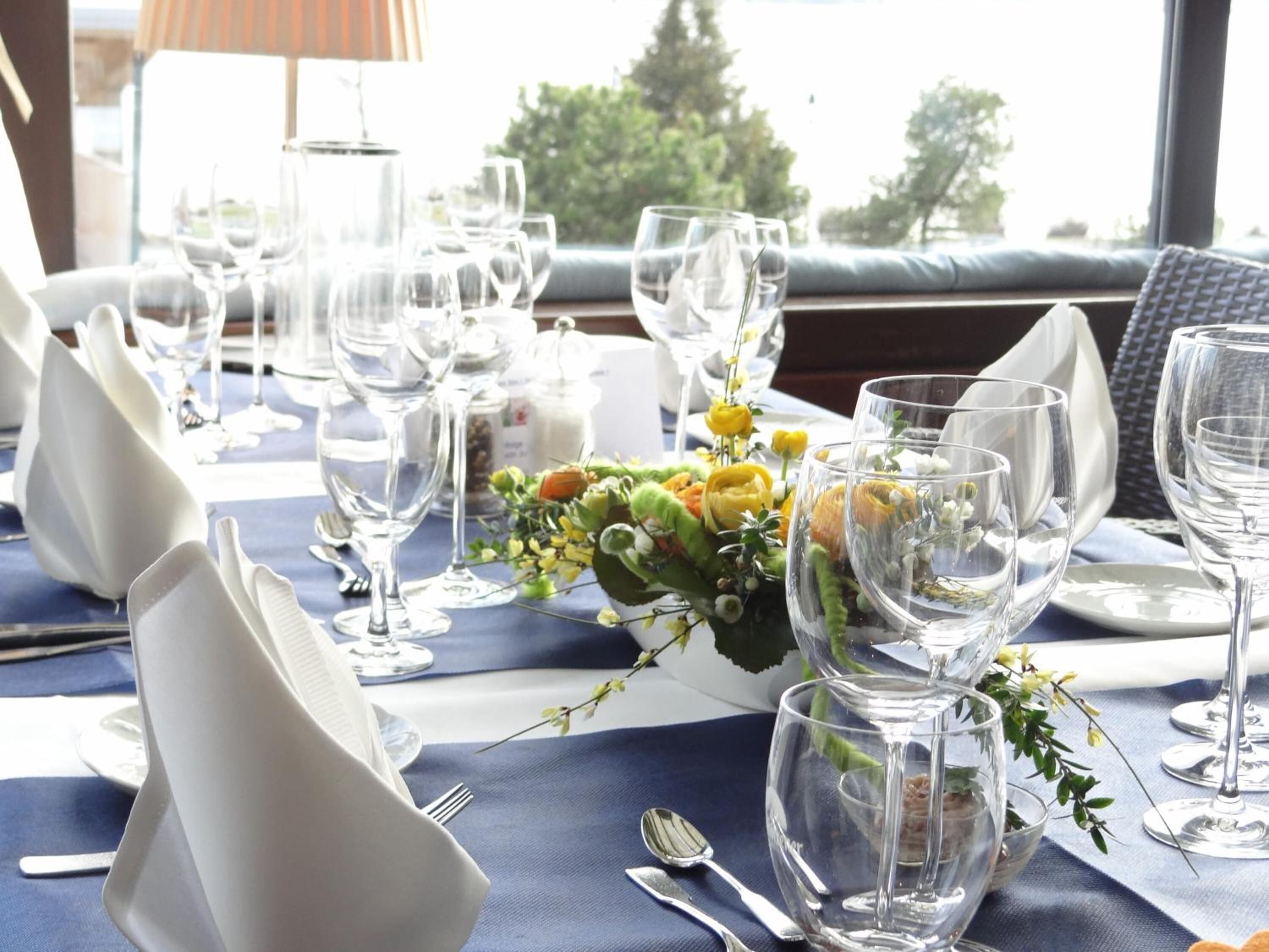 A dining table set with multiple wine glasses, plates, and cutlery, with a floral centerpiece.