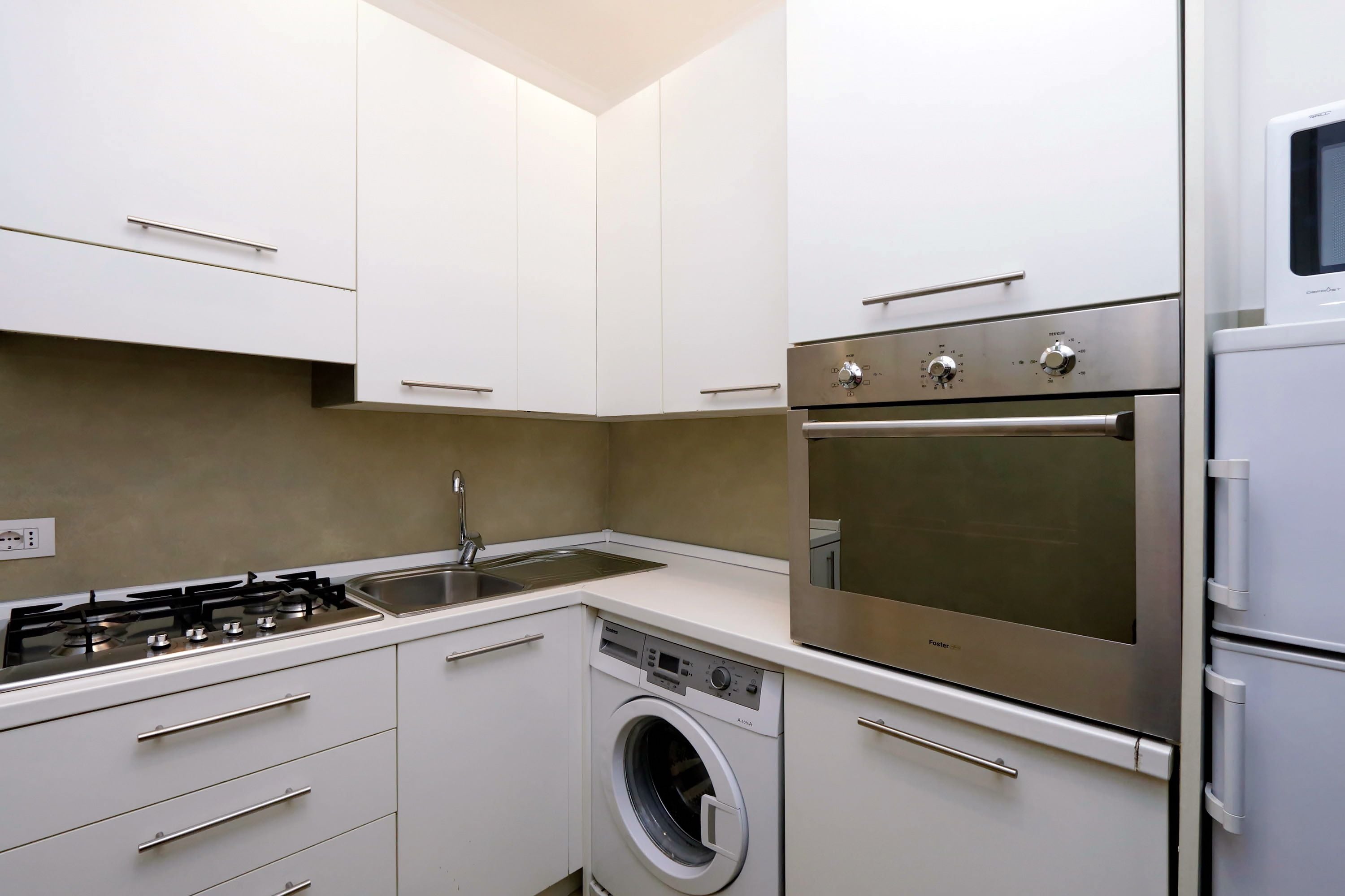 Une cuisine compacte équipée d’une cuisinière à gaz, d’un four encastré, d’un lave-vaisselle et d’une machine à laver.
