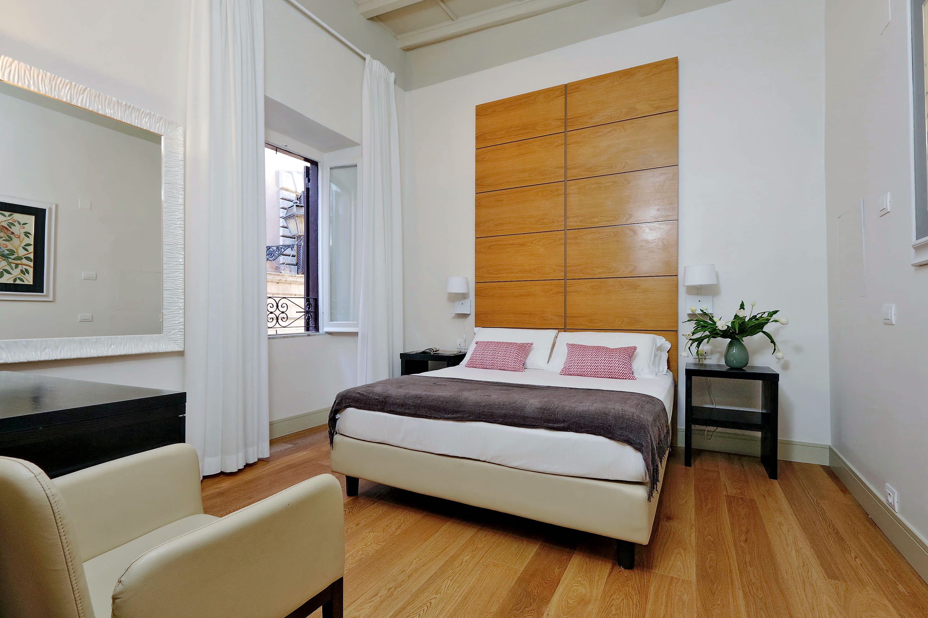 Une chambre à coucher comprenant un lit, un bureau, une chaise, une table de chevet et une plante en pot.
