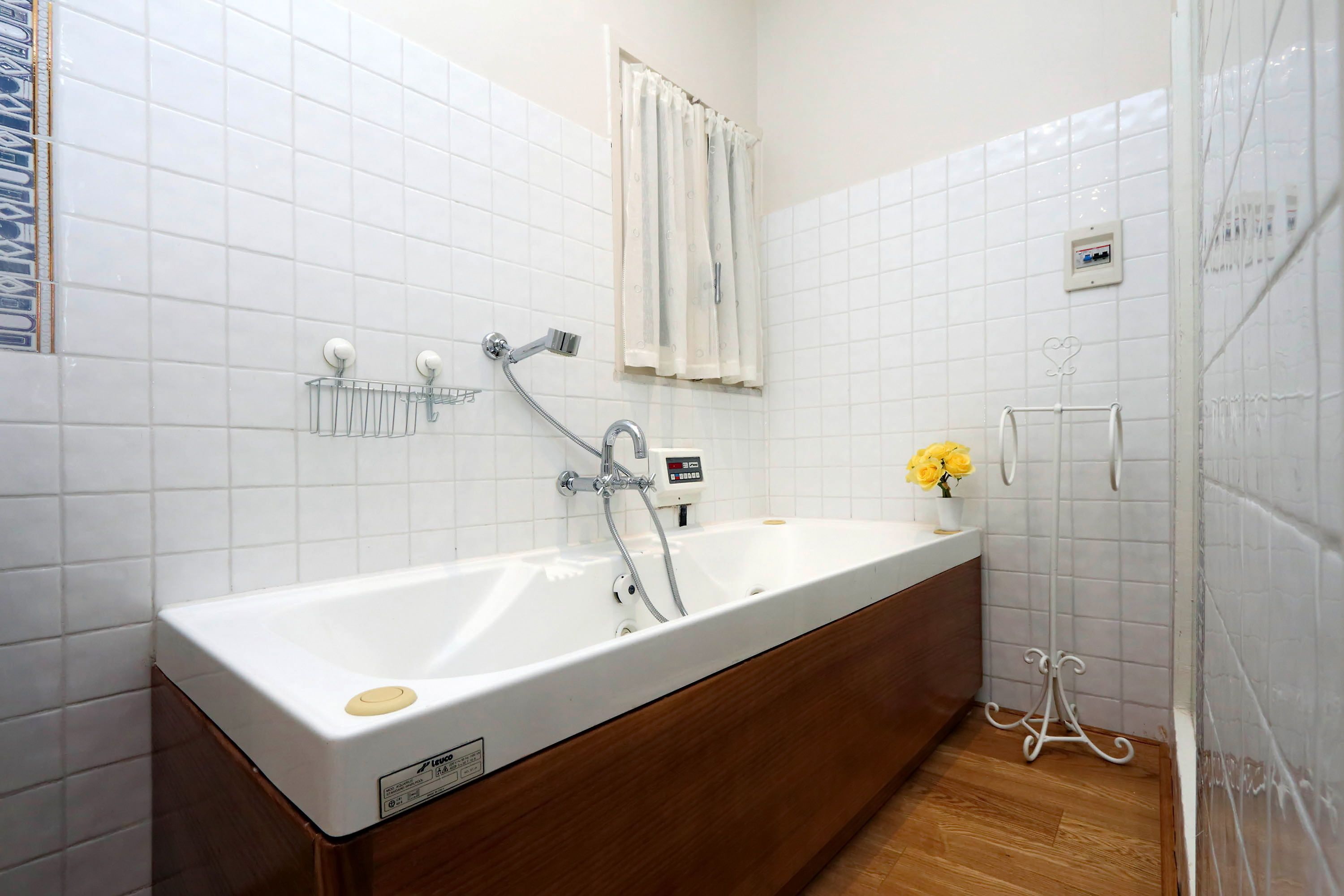 A bathroom with a white bathtub, a wooden vanity, a towel rack, and a shower area.