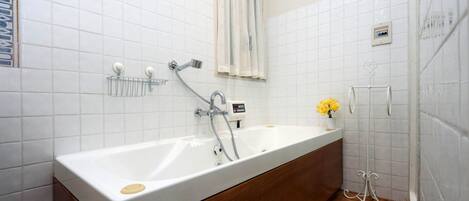 A bathroom with a white bathtub, a wooden vanity, a towel rack, and a shower area.