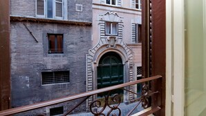 A view of a building with a wrought iron balcony railing, a green door, and multiple windows with shutters. - Farnese Charme - My Extra Home (Rome)