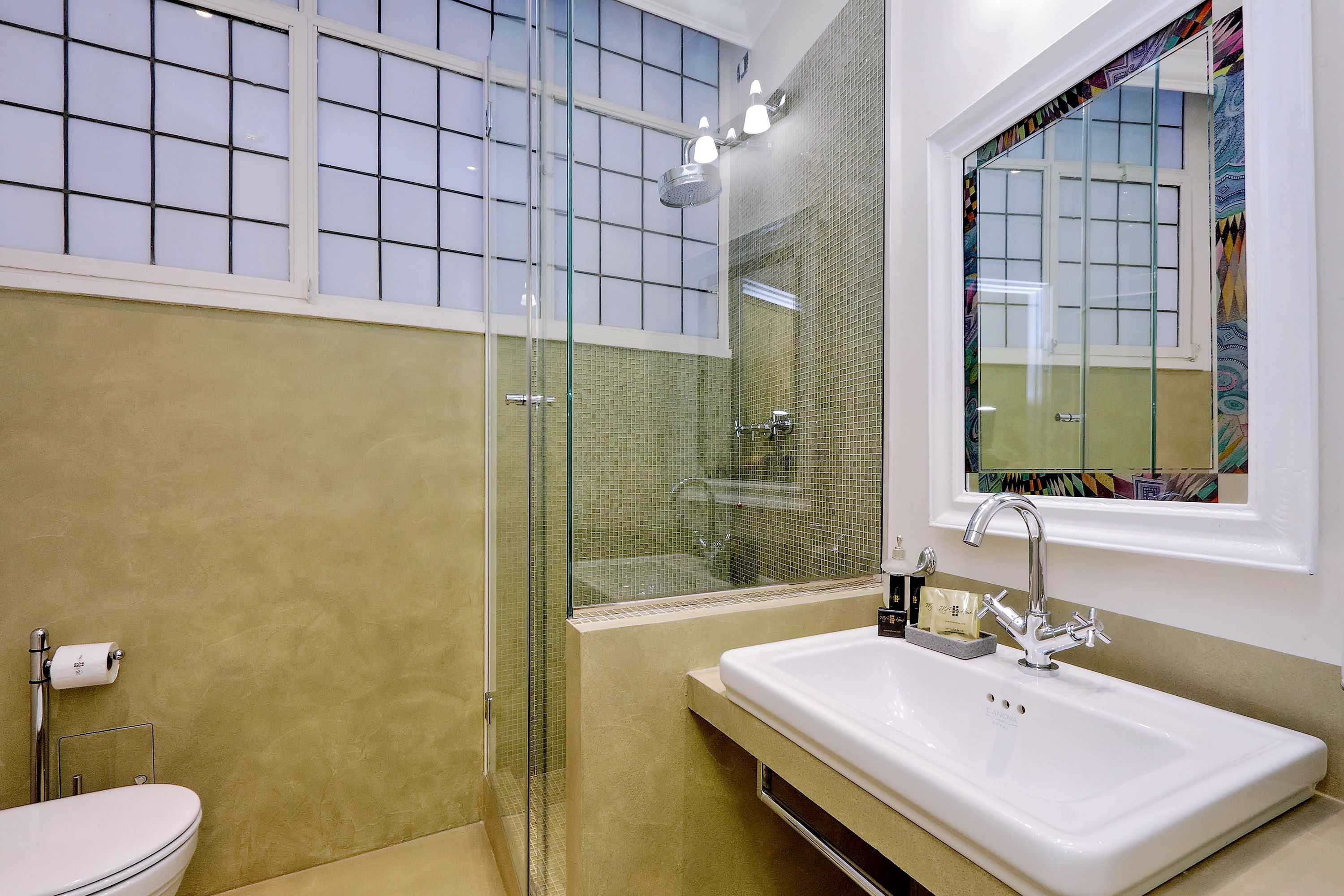 A bathroom with a glass-enclosed shower, a white sink, and a toilet.