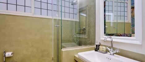 A bathroom with a glass-enclosed shower, a white sink, and a toilet.