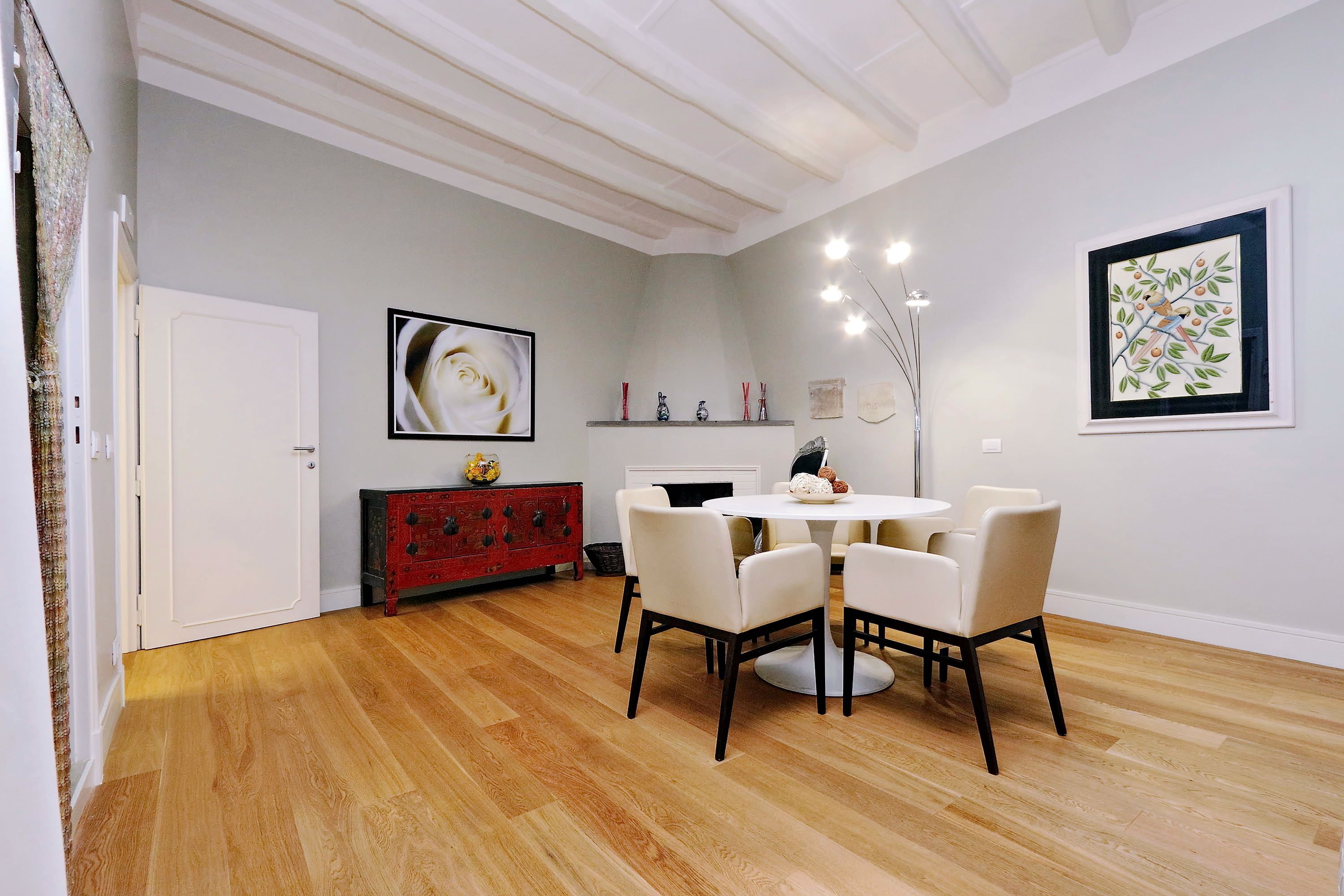 A dining area with a round table and chairs, a red dresser, a fireplace, and wall art.