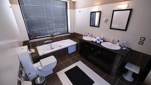 A modern bathroom with a bathtub, two sinks, and a toilet. - Lilies Villa (Rhodes)