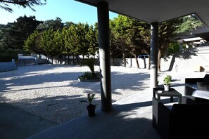 An outdoor patio area with a gravel ground, potted plants, and outdoor furniture. - Lilies Villa (Rhodes)