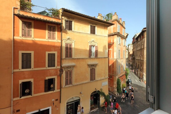 A narrow street with buildings featuring arched doorways and traditional shutters. - Giulia Charme - My Extra Home (Rome)