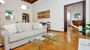 Una sala de estar moderna con una mesa de centro de vidrio, un sofá blanco, piso de madera y techo de madera.