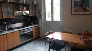 A kitchen with wooden cabinets, a stove, and a dining table with chairs. - La Capitale B&B (Rome)