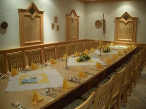 A long dining table set for a meal with multiple chairs, candles, and table settings.
