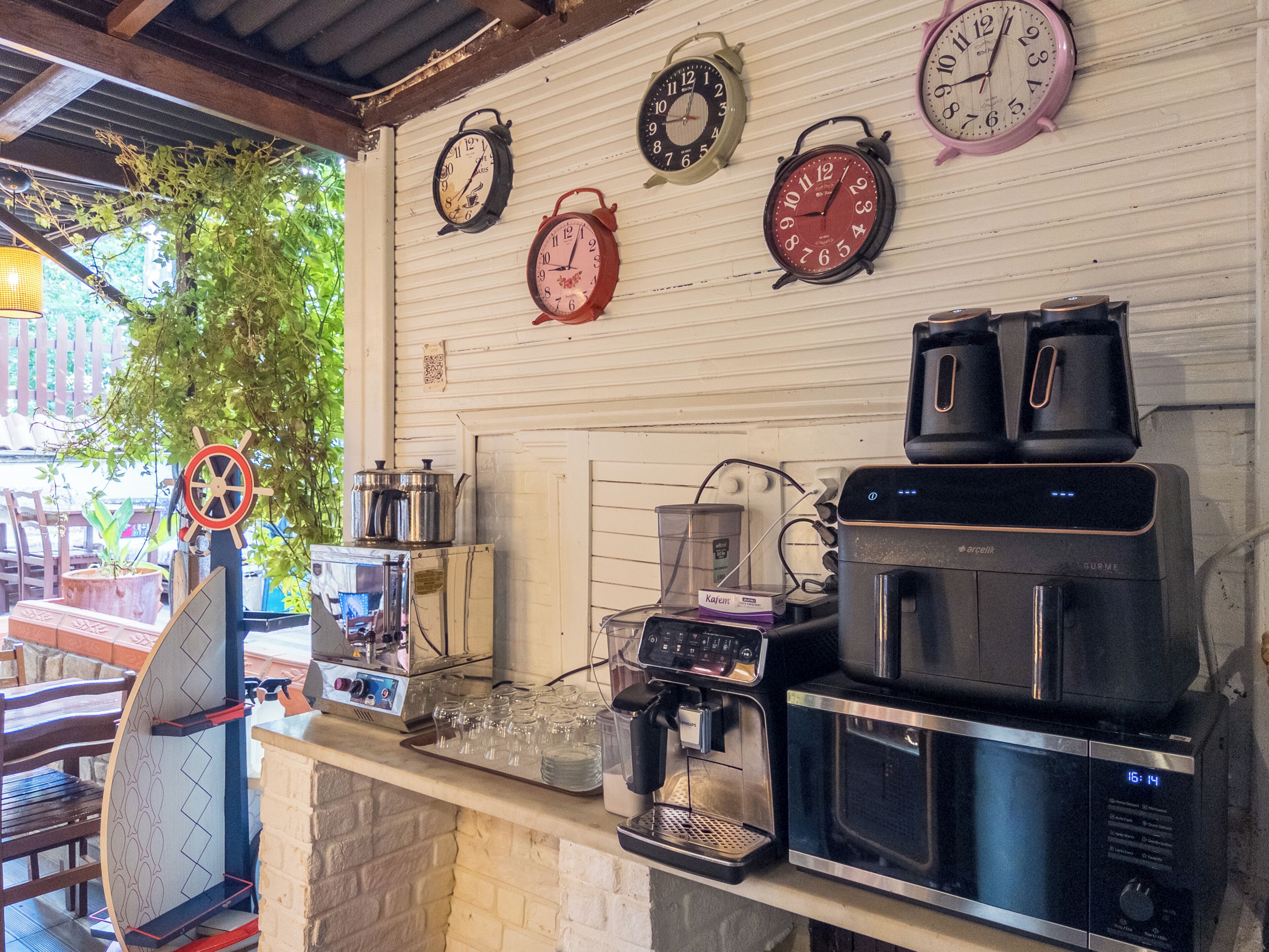 A kitchen area with a coffee machine, a microwave, and four wall clocks.