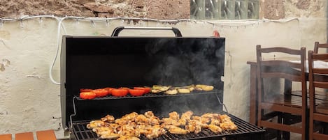 A barbecue grill with chicken and vegetables being cooked.