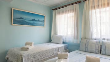 Une chambre d’hôtel avec deux lits, un tableau au mur et une fenêtre avec des rideaux.